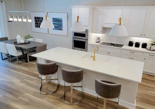 white kitchen and dining room with dark chairs and gold fixtures
