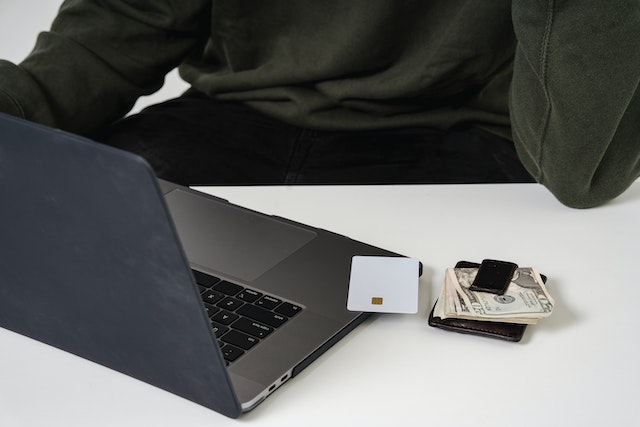 an open laptop with a credit card and money clip next to it