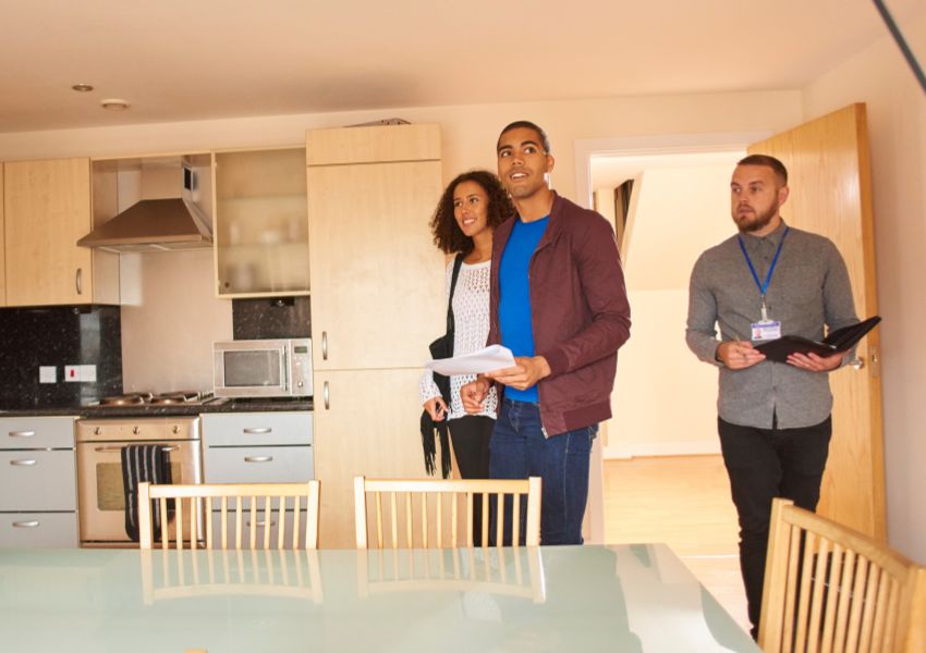 A couple of tenants taking a tour of a rental property with a property manager in the background