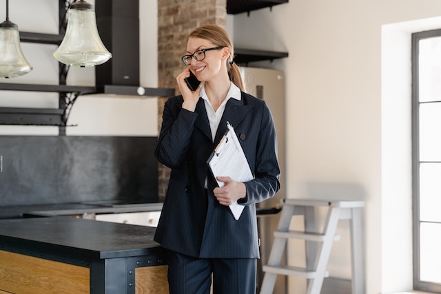 person in a suit speaking on the phone and holding a clipboard following an inspection