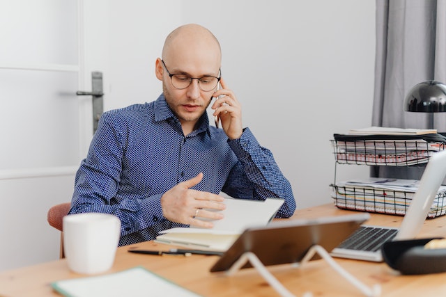 property manager in blue shirt speaking on the phone while reviewing a document