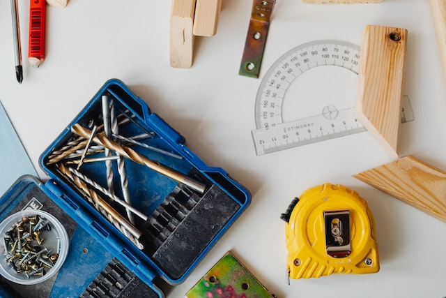 a bunch of tools, nails, screws, and a tape measurer on a table