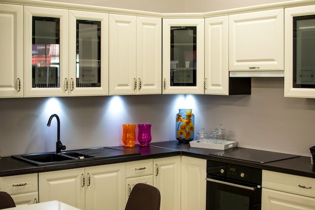 a kitchen with dark granite counters and white cabinets with built-in lighting