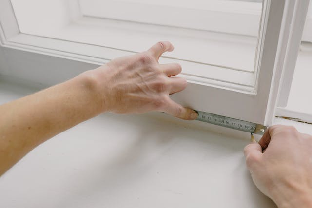 maintenance person marking measurements for a window repair